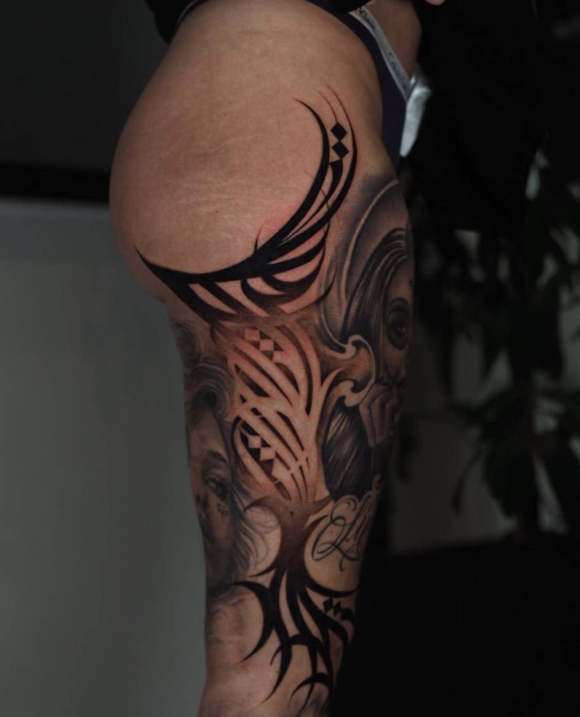 Side view of man's shoulder and upper arm featuring bold tribal-inspired black tattoo with geometric elements